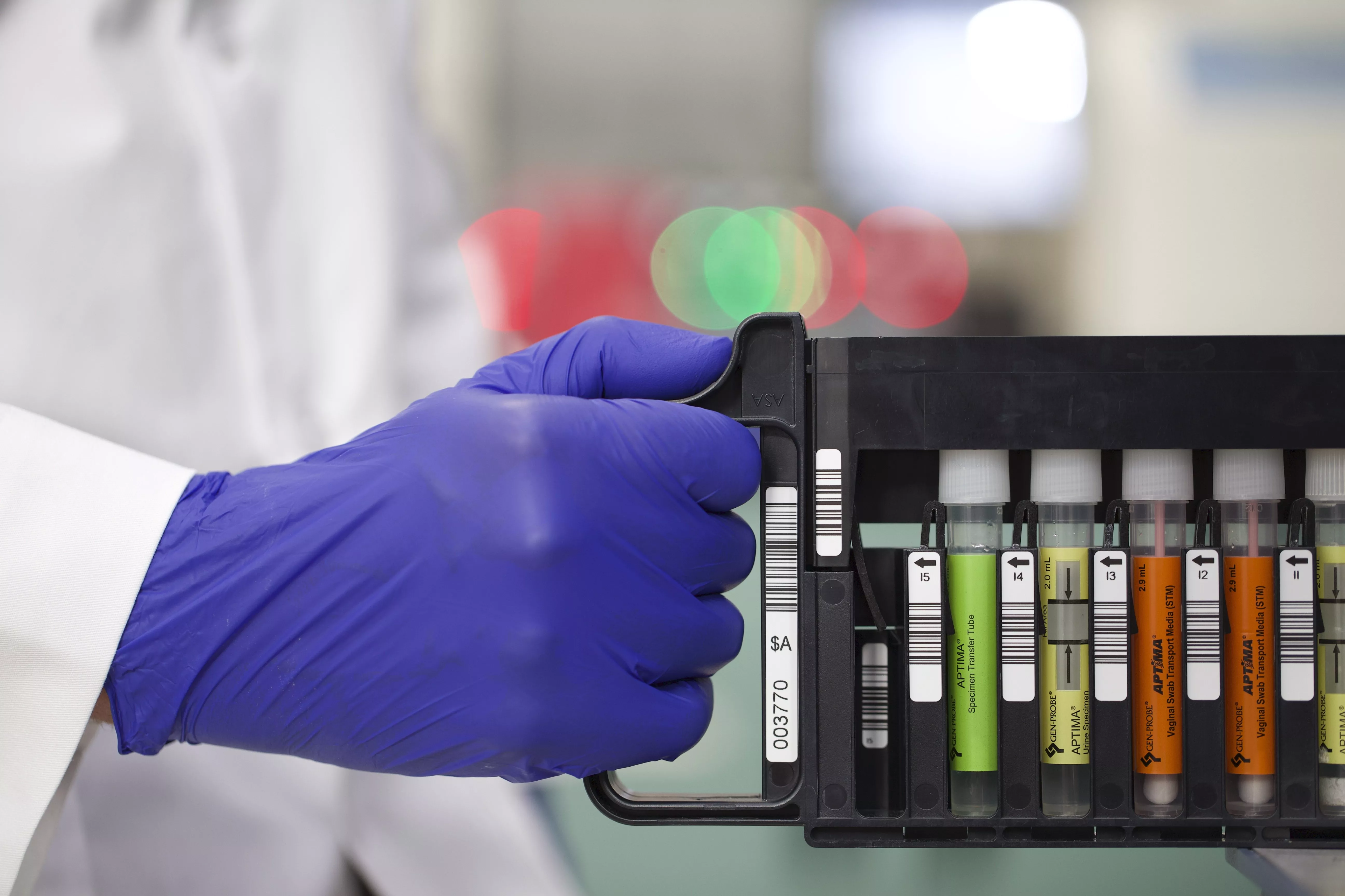 Gloved hand pushing a tray of vials