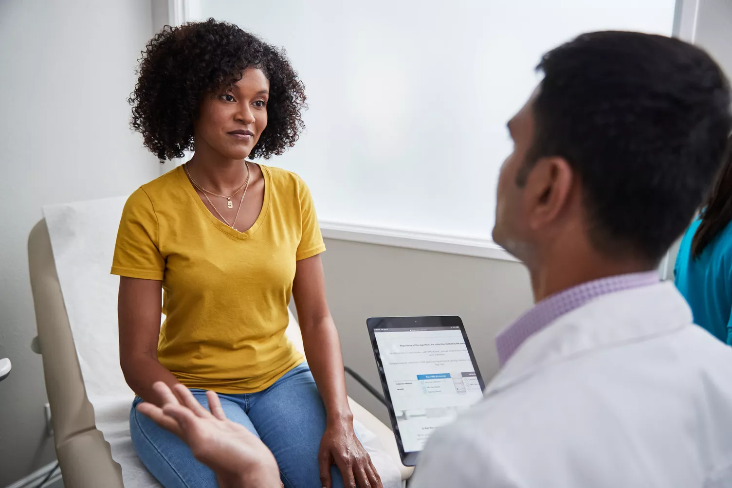 Physician speaking with patient in clinic room.