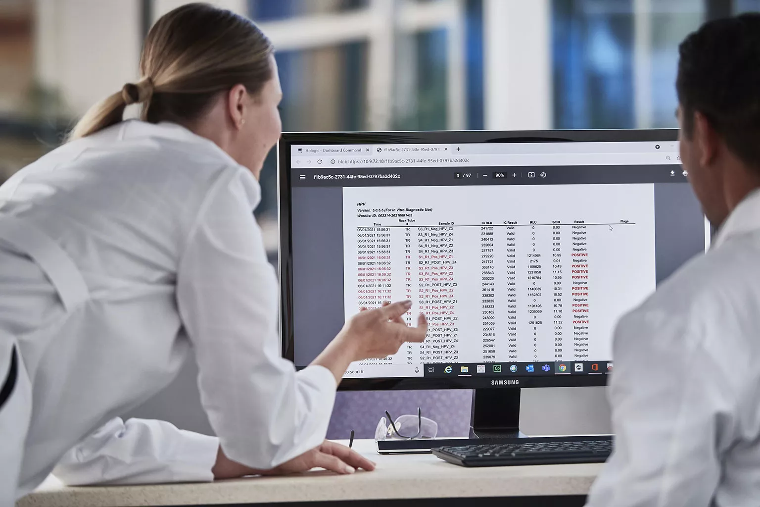 image of lab technicians looking at data on a monitor in a lab setting.