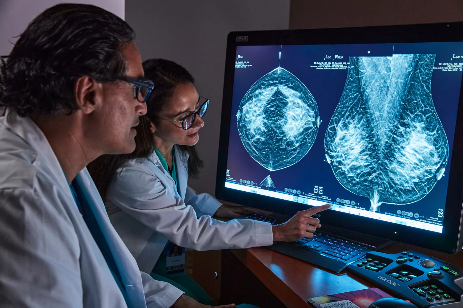 healthcare professional pointing and looking at scans on monitor