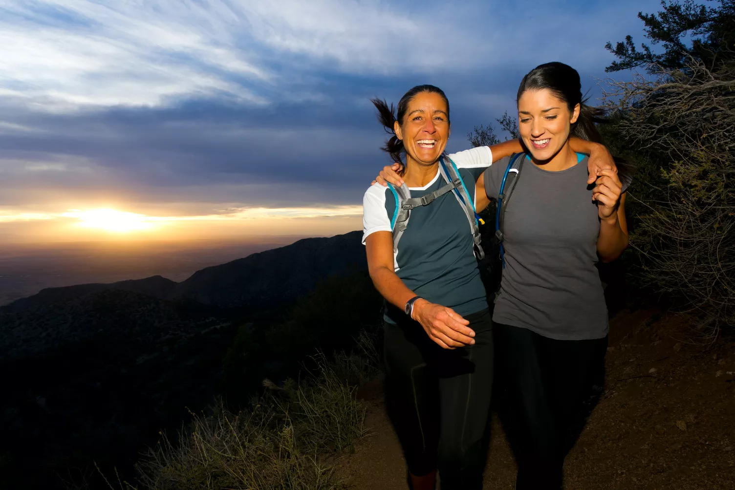 2 women hiking outside at sunset