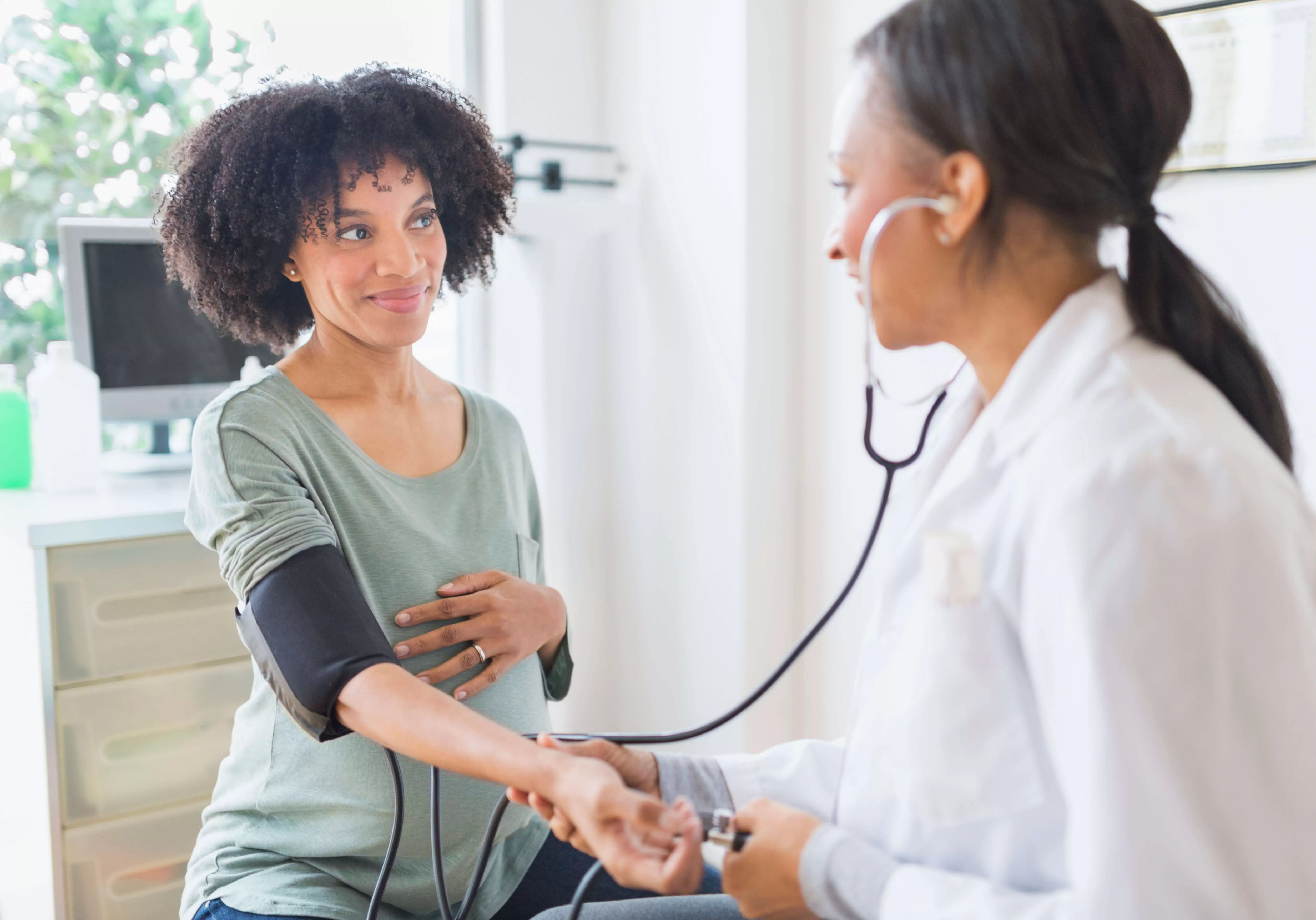 Female physician uses stethoscope on woman's arm.