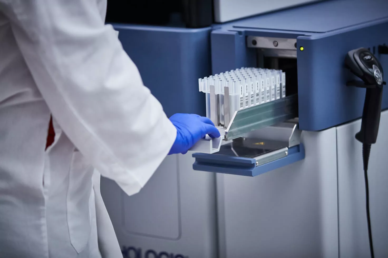 Lab technician pushing in tray of vials into medical system